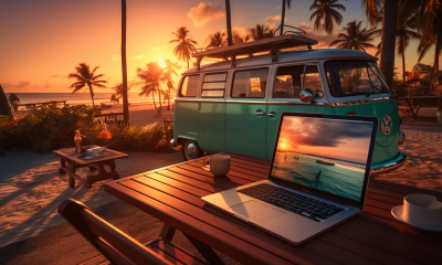 Image of a laptop on a table at the beach at sunset with a VW bus in the background